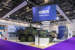 Overall view of the KNDS booth with a large blue banner reading ‘KNDS – When It Counts’ and a displayed Leopard 2 military vehicle.