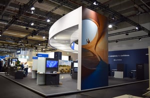 Overall view of the Trimble booth with curved white elements, modern screens, and open meeting areas.