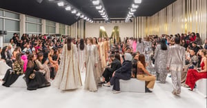 Mehrere Models auf dem Laufsteg bei der Dubai Fashion Week, elegante Outfits, Publikum sitzt beidseitig entlang des Laufstegs.