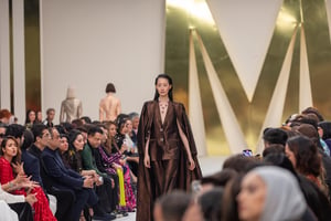 Model auf dem Laufsteg während der Dubai Fashion Week, umgeben von Publikum auf beiden Seiten, in einem hell beleuchteten Veranstaltungsraum.
