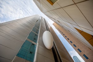 Modern tall building with glass windows and metallic surfaces, photographed against a partly cloudy sky.