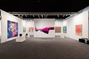 Room with modern artworks on the walls, including a large image of a pink hand and abstract paintings.