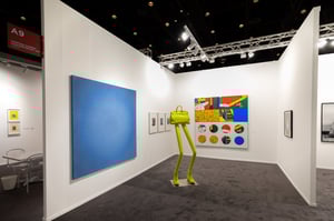 Large blue painting on the wall, next to a yellow chair-shaped sculpture and several smaller pictures.