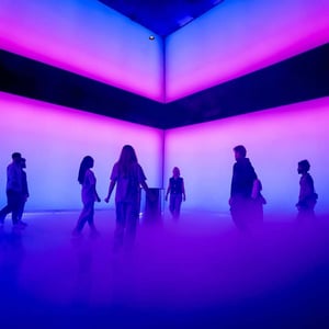 Group of people in a room illuminated with purple and pink lights and floor fog during the Dubai Future Foundation Event..