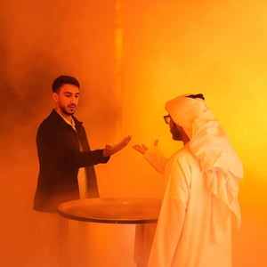 Two people in an orange-lit space, one handing an object to the other during the Dubai Future Foundation Event.