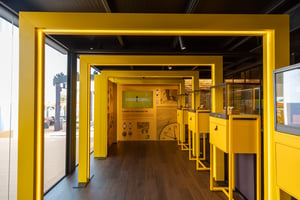 Innenansicht des Breitling‑Ausstellungsbereichs mit leuchtend gelben Präsentationsflächen, Uhrenvitrinen und markentypischen Gestaltungselementen.