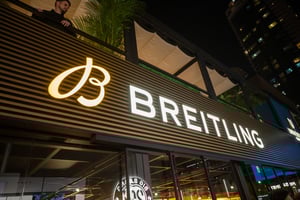 Nahaufnahme der beleuchteten Breitling‑Beschriftung am Pavillon der Dubai Watch Week 2025 mit moderner Lamellenfassade.