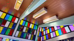 Interior space with colorful stained glass windows and ceiling lights hanging from a wooden ceiling, creating an artistic atmosphere.