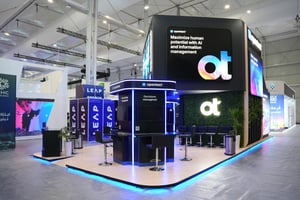 Front view of the OpenText booth showcasing prominent branding and several interactive stations for visitors.