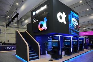 OpenText booth at LEAP 2025 featuring a large black structure, illuminated logo, and multiple workstations with screens.
