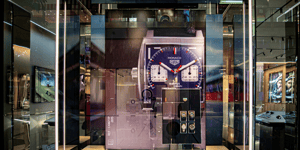 TAG Heuer Schaufenster mit überdimensionalem Zifferblatt und sichtbaren mechanischen Komponenten. Innenraum hell beleuchtet mit Uhren-Displays.