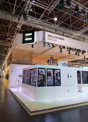 Brückner Group booth at K 2025 featuring a modern, open design with large machinery and clear brand presentation.