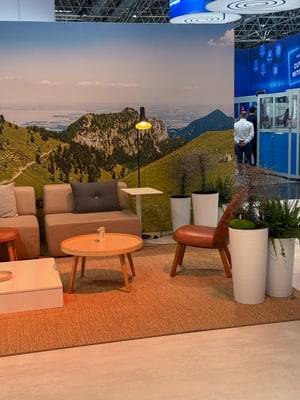 Lounge area of the Brückner Group booth with comfortable seating and a wall graphic depicting a mountain landscape.