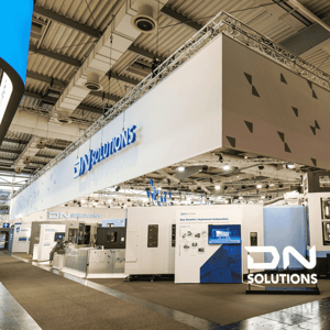 A modern exhibition stand by DN Solutions featuring large-scale brand displays, machine tools and open presentation areas for trade visitors.