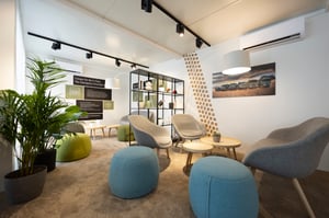 Modern gestalteter Lounge- und Besprechungsbereich mit Sitzmöbeln, Pflanzen und Informationswänden im Mercedes-Benz Defence Trucks Messestand.