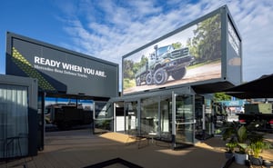 Außenansicht des Mercedes-Benz Defence Trucks Messestands mit großformatigem LED-Screen, Markenbotschaft und Containerarchitektur.