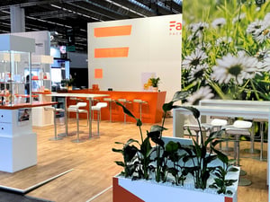 Better Stands Gold award-winning exhibition stand for Faller Packaging, showcasing a daisy-themed design and distinctive orange design elements.