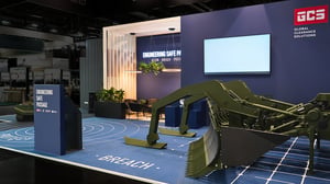 Nahaufnahme eines militärischen Räumgeräts auf dem GCS-Messestand. Das Exponat steht vor einer modernen Markenarchitektur mit digitalen Präsentationsflächen und grafisch gestaltetem Boden.