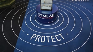 Detailaufnahme des Bodendesigns am GCS-Messestand mit konzentrischen Kreisen und dem Schriftzug „PROTECT“. Im Zentrum befindet sich ein Präsentationssockel mit einem technischen Exponat.