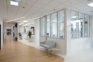 Ein heller Flur, der zu verschiedenen Büros oder Besprechungsräumen führt, teilweise durch Glaswände getrennt.