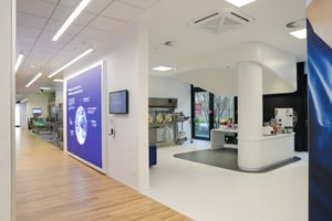 Ein heller Flur mit Informationswänden und einem Blick in ein Labor oder technischen Raum.