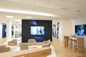 Ein moderner Empfangsbereich mit bequemen Sitzgelegenheiten und einem großen Bildschirm an der Wand.