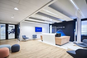 Ein Empfangsbereich mit modernen Möbeln und einem großen Bildschirm hinter dem Empfangstresen.