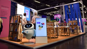 Bereich des Haufe Group Messestandes mit Infoterminals, Büchern und einem Roboter-Element als Blickfang.