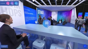 Workshop-Bereich am virtuellen Haufe-Messestand mit großer blauer Infotafel und Teilnehmern an einem langen Tisch.