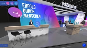 Virtueller und moderner Haufe-Messestand mit dem Slogan „Erfolg durch Menschen“ und Empfangstresen mit Barhockern.