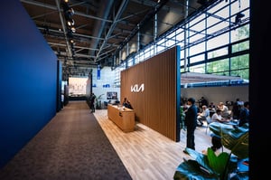 Eingangsbereich des Kia Messestands auf der IAA Transportation 2026 mit hochwertiger Holzarchitektur, Empfangsbereich und Lounge-Zonen.