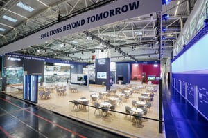 Messestand von Krones auf der drinktec 2025 mit großem offenen Sitzbereich, modernen Displays und klarer Markenpräsentation.