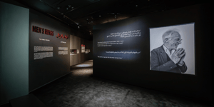 An exhibit area presents wall texts in English and Arabic along with a black-and-white photograph of an elderly person related to the theme “Men’s Rings.”