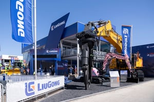 Outdoor view of LiuGong’s booth at bauma 2025 featuring large construction machinery, including a yellow excavator. LiuGong branding visible on flags and signage. 