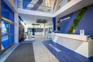 Reception area of LiuGong’s booth with a welcome desk, branded decor, and a vertical green wall.