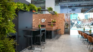 Communication and hospitality area at the MS Motorservice exhibition stand combining workshop-inspired design, greenery and premium material finishes.