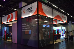 Eckansicht des Rexx Systems Messestandes mit bedruckter übers Eck gehender Wandverkleidung.