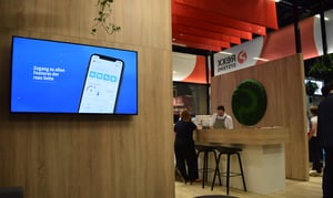Innenansicht des Rexx Systems Messestandes mit einem LED-Display, das unterschiedliche Informationen anzeigt, und der Hospitality-Station, an der Kaffee serviert wird.