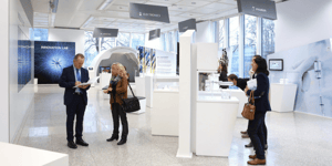 Ein weiterer Bereich des Ausstellungsraums zeigt verschiedene Exponate und ein großes Poster über eine Produktionsstätte. Ein weiteres Schild trägt die Aufschrift „INNOVATION LAB“.
