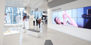 Zwei Personen stehen in einem modernen Ausstellungsraum und unterhalten sich. Im Hintergrund ist ein Schild mit der Aufschrift „INNOVATION LAB“ zu sehen.