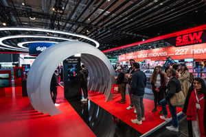 A large, round exhibit at the SEW stand, with various visitors examining it.