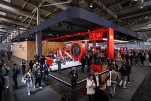 Gesamtansicht des SEW EURODRIVE Messestandes mit markantem roten Design, kreisförmigem Exponat und zahlreichen Besuchern, die sich über Antriebstechnik und Automatisierungslösungen informieren.
