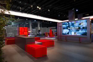 Präsentationszone des SEW EURODRIVE Messestandes mit großen Displays und Exponaten für Automobil- und Industrieanwendungen.