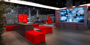 Presentation zone of the SEW-EURODRIVE booth with large screens and exhibits for automotive and industrial applications.