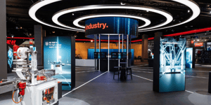 Section of the SEW-EURODRIVE booth with circular lighting installations and exhibits for industrial applications and robotics.
