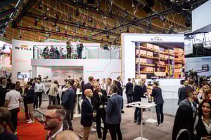 Messestand von STILL auf der LogiMAT 2024 mit großem Display, das Lagerlösungen zeigt. Zahlreiche Besucher erkunden den Stand und informieren sich über Intralogistik-Technologien.