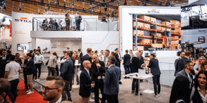 Messestand von STILL auf der LogiMAT 2024 mit großem Display, das Lagerlösungen zeigt. Zahlreiche Besucher erkunden den Stand und informieren sich über Intralogistik-Technologien.