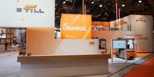 STILL information counter with orange brand graphics and open structures at the LogiMAT 2026 trade booth.