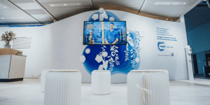 Information point at Sappi's exhibition booth with paper covered seating options, paper decorations and a TV screen with informational information.
