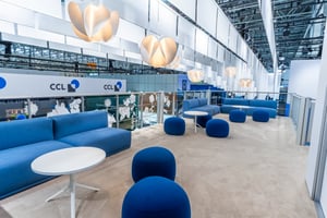 Der zweite Stock der Sappi-Ausstellungsfläche mit hellen Teppichen, blauen Möbeln und Papierlampen.